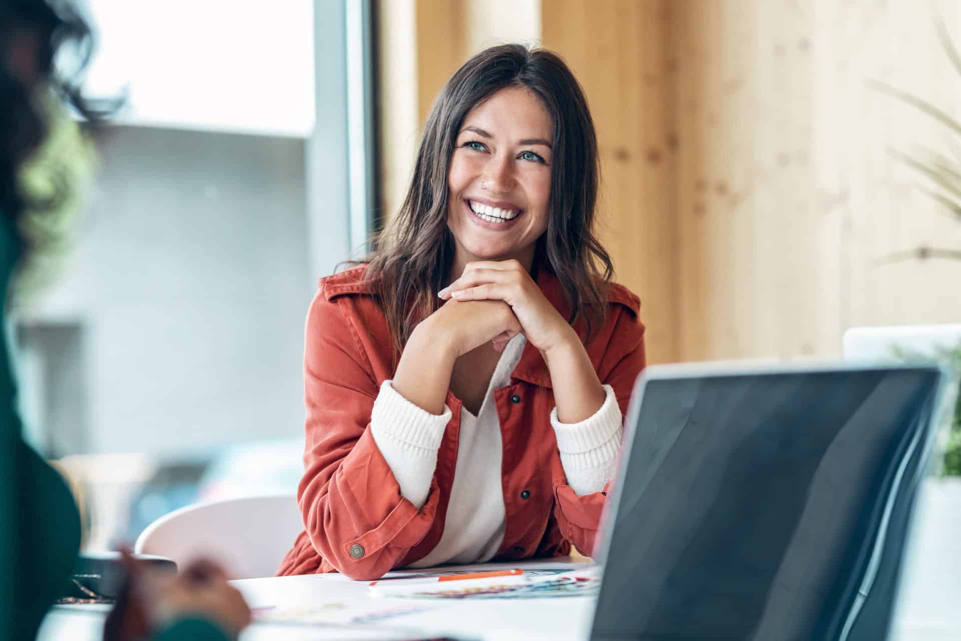 Smiling young business woman listening her partner on coworking
