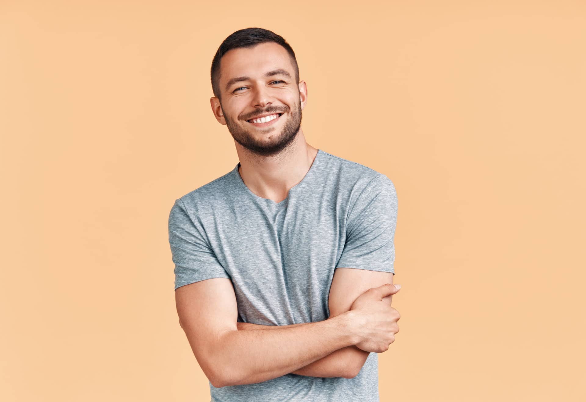 Happy smiling handsome man with crossed arms looking to camera o
